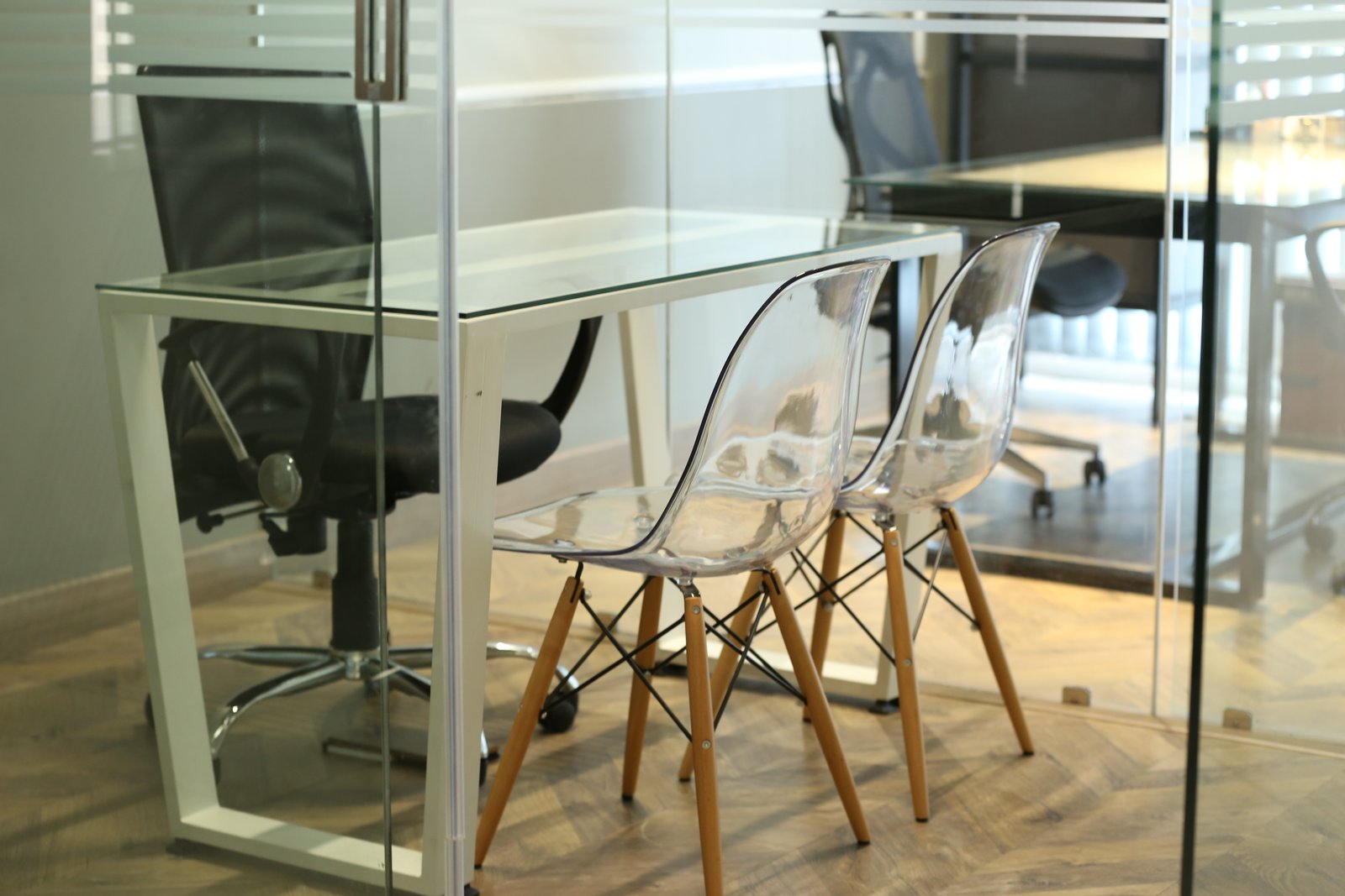 Glass meeting room with transparent chairs by Humming House